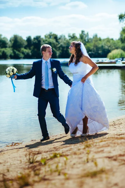 Kärleksfull bröllop par står och kysser nära vatten — Stockfoto