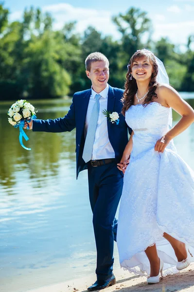 Liefdevolle bruidspaar permanent en kussen in de buurt van water — Stockfoto