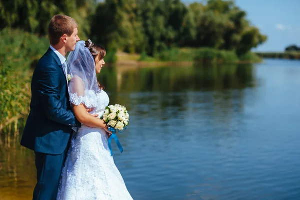 Kjærlig ektepar som står og kysser nær vann – stockfoto