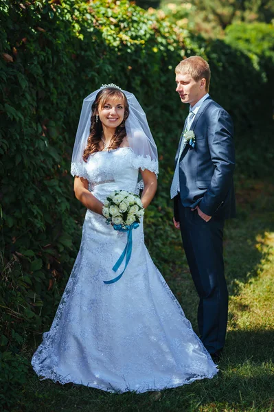 Nevěsty a ženicha na svatební den chůze venku na jarní přírody. Svatební pár, Happy novomanželský pár objímat v parku. — Stock fotografie