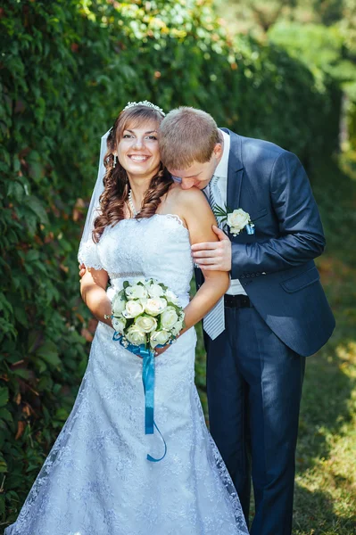 Novia y novio en el día de la boda caminando al aire libre en la naturaleza de primavera. Pareja nupcial, feliz pareja recién casada abrazándose en el parque verde . — Foto de Stock