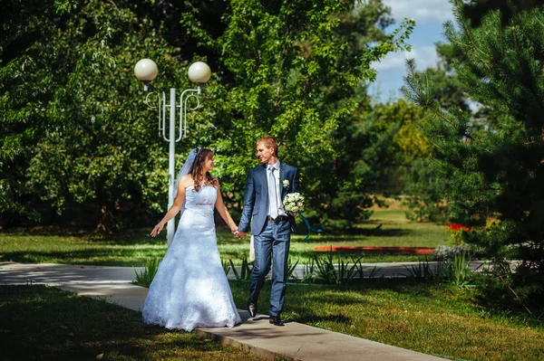 Bruid en bruidegom op bruiloft dag buiten lopen op lente aard. Bruidspaar, gelukkig jonggehuwde paar omarmen in groen park. — Stockfoto
