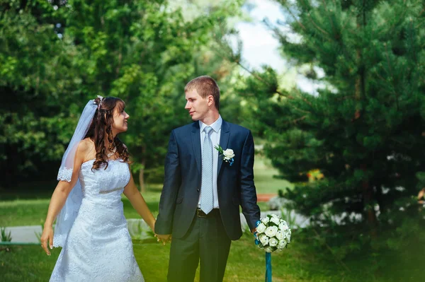 Noiva e noivo no dia do casamento andando ao ar livre na natureza de primavera. Casal nupcial, casal recém-casado feliz abraçando no parque verde . — Fotografia de Stock