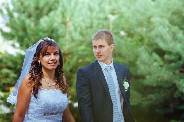 Pengantin wanita dan pengantin pria pada hari pernikahan berjalan di luar ruangan pada musim semi. Pasangan pengantin, Happy pasangan pengantin baru merangkul di taman hijau . — Stok Foto