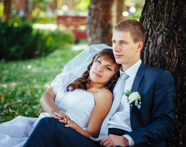 Novia y novio en el día de la boda caminando al aire libre en la naturaleza de primavera. Pareja nupcial, feliz pareja recién casada abrazándose en el parque verde . — Foto de Stock