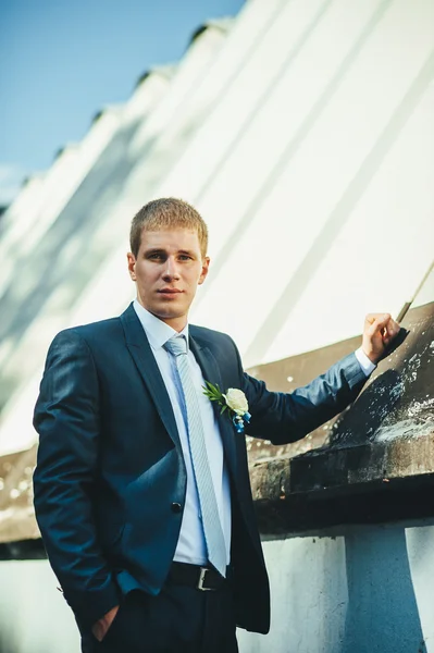 Feliz guapo novio caucásico en esmoquin pensando y poniéndose su corbata . — Foto de Stock