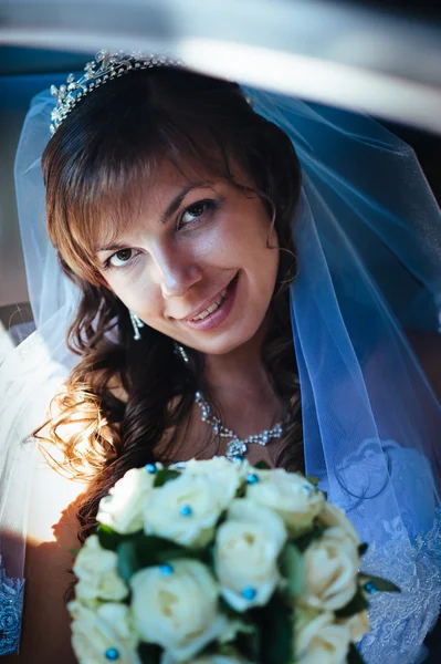 Close-up portrait of pretty shy bride in a car window — Stock Photo, Image