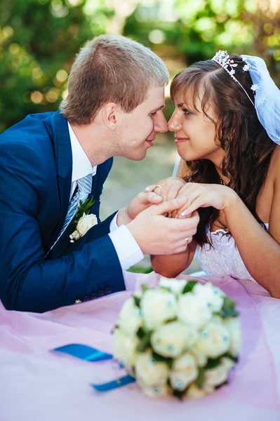 Noiva e noivo posando na mesa de banquetes decorados no parque de verão  . — Fotografia de Stock
