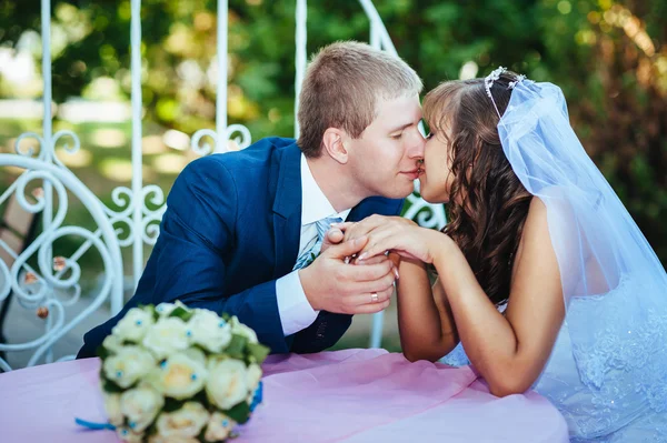 Noiva e noivo posando na mesa de banquetes decorados no parque de verão  . — Fotografia de Stock