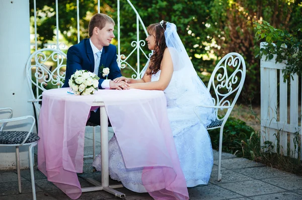 Sposo e sposo in posa al tavolo da banchetto decorato nel parco estivo  . — Foto Stock