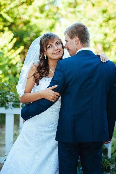 Braut und Bräutigam am Hochzeitstag beim Spaziergang in der Natur des Frühlings. Brautpaar, glückliches Brautpaar umarmt sich im grünen Park. — Stockfoto