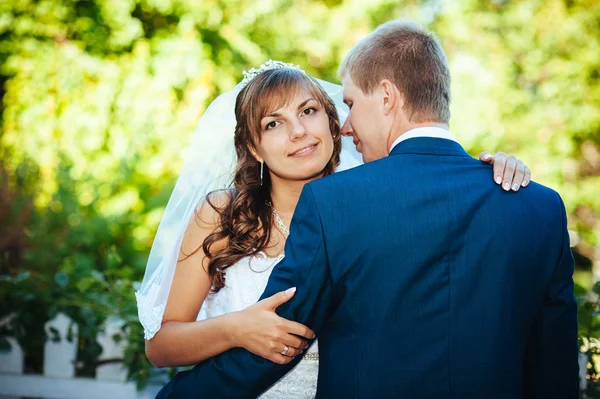 Gelin ve damat gün açık havada yürüyüş düğününde Doğa bahar. Gelin çift, mutlu yeni evli çift yeşil park kucaklayan. — Stok fotoğraf