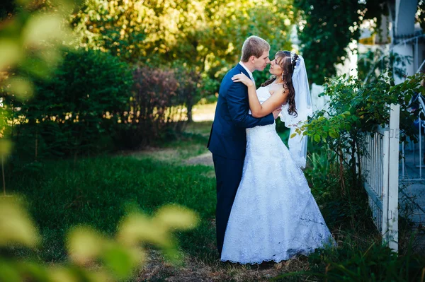 Νύφη και το γαμπρό στο περπάτημα σε εξωτερικούς χώρους στη ημέρα γάμου άνοιξη φύση. Νυφικό ζευγάρι, ευτυχής νεόνυμφο ζευγάρι αγκαλιάζει στο καταπράσινο πάρκο. — Φωτογραφία Αρχείου