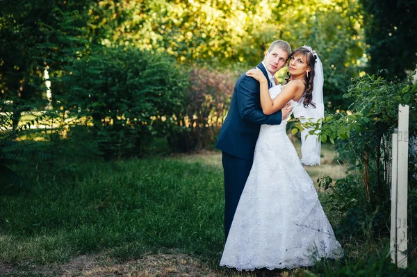 Noiva e noivo no dia do casamento andando ao ar livre na natureza de primavera. Casal nupcial, casal recém-casado feliz abraçando no parque verde . — Fotografia de Stock