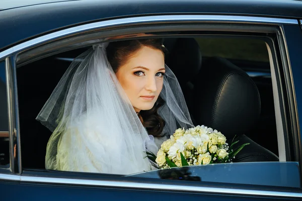 Close-up portrait of pretty shy bride in a car window — Stock Photo, Image