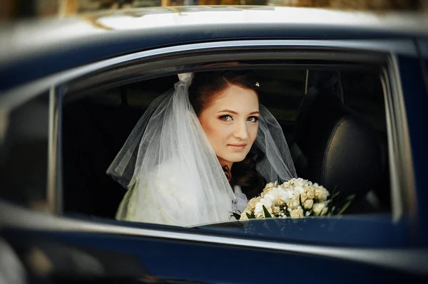 Close-up portrait of pretty shy bride in a car window — Stock Photo, Image