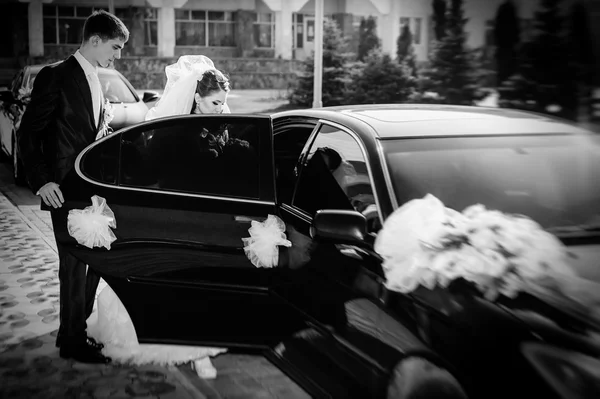 Bride and groom kissing in limousine on wedding-day. — Stock Photo, Image