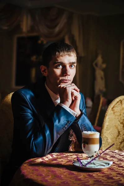 Handsome man drinking coffee at in cafe. Grooms hands holding cup of coffee. — Stock Photo, Image