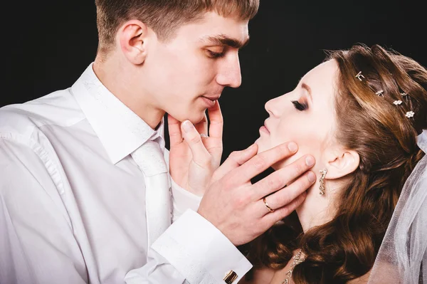 Groom kissing bride on wedding. Black background. — Stock Photo, Image