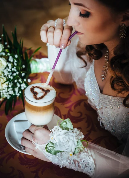 Bride in luxurious restaurant drink cup of Cappuccino or latte coffee with heart shape on her wedding. Valentines day — Stock Photo, Image