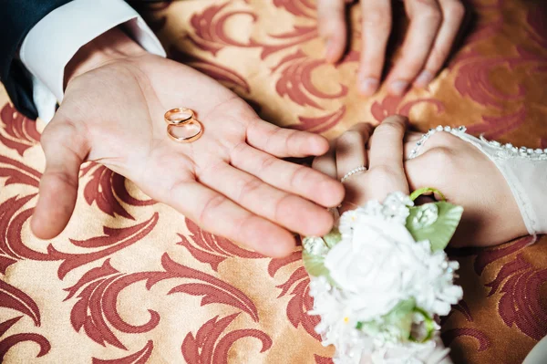 Bröllop par händer på bordet och ringar, brudbukett blommor — Stockfoto