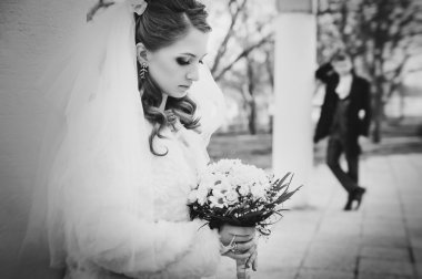 Şık gelin ve damat düğün günü dışarıda birlikte poz veriyorlar.