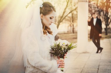 Şık gelin ve damat düğün günü dışarıda birlikte poz veriyorlar.