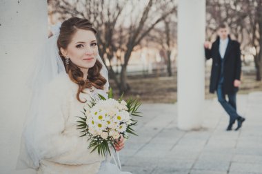 Şık gelin ve damat düğün günü dışarıda birlikte poz veriyorlar.