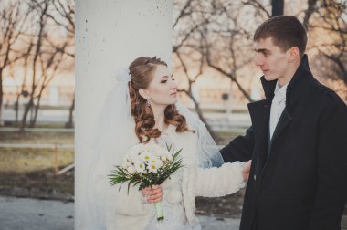 Şık gelin ve damat düğün günü dışarıda birlikte poz veriyorlar.