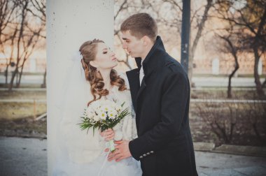 Şık gelin ve damat düğün günü dışarıda birlikte poz veriyorlar.