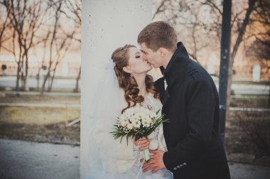 Şık gelin ve damat düğün günü dışarıda birlikte poz veriyorlar.