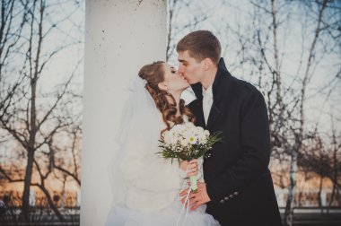 Şık gelin ve damat düğün günü dışarıda birlikte poz veriyorlar.