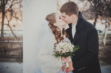 Şık gelin ve damat düğün günü dışarıda birlikte poz veriyorlar.