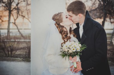 Şık gelin ve damat düğün günü dışarıda birlikte poz veriyorlar.