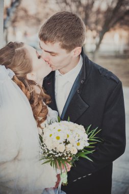 Şık gelin ve damat düğün günü dışarıda birlikte poz veriyorlar.