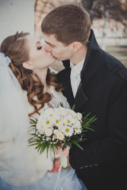 Şık gelin ve damat düğün günü dışarıda birlikte poz veriyorlar.