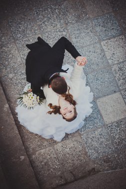 Şık gelin ve damat düğün günü dışarıda birlikte poz veriyorlar.