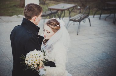 Şık gelin ve damat düğün günü dışarıda birlikte poz veriyorlar.