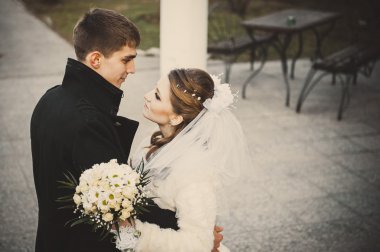 Şık gelin ve damat düğün günü dışarıda birlikte poz veriyorlar.