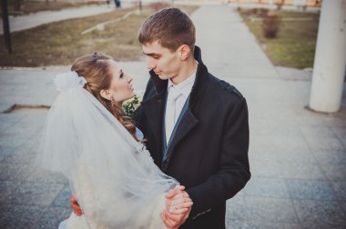 Şık gelin ve damat düğün günü dışarıda birlikte poz veriyorlar.