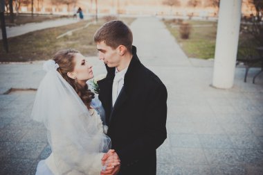 Şık gelin ve damat düğün günü dışarıda birlikte poz veriyorlar.