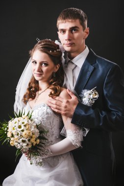 Gelin ve damat öpüşme, sarılma. siyah arka plan üzerine stüdyoda çekilmiş düğün fotoğrafı