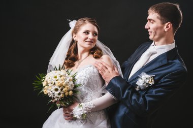 Gelin ve damat öpüşme, sarılma. siyah arka plan üzerine stüdyoda çekilmiş düğün fotoğrafı