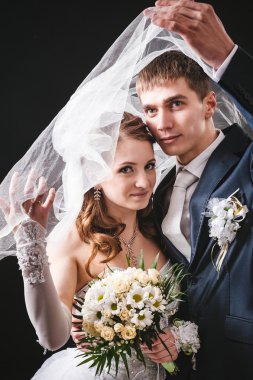 Gelin ve damat öpüşme, sarılma. siyah arka plan üzerine stüdyoda çekilmiş düğün fotoğrafı