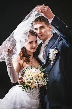 Gelin ve damat öpüşme, sarılma. siyah arka plan üzerine stüdyoda çekilmiş düğün fotoğrafı