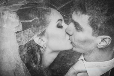 Gelin ve damat öpüşme çiçek buketi elinde tutan peçe altında. siyah arka plan