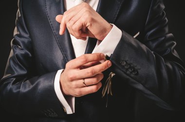 Takım elbiseli hazırlanıyor düğün damat elleri. siyah stüdyo arka plan