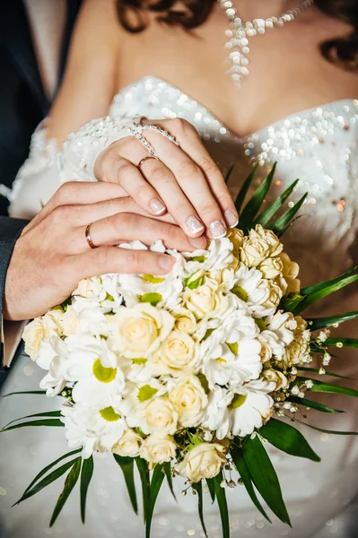 Mãos com anéis de casamento no buquê nupcial de flores — Fotografia de Stock