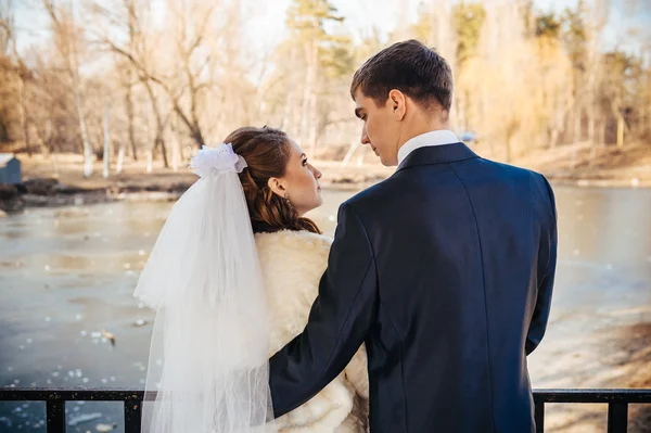 Bruden och brudgummen kramas på sjön i en park. Bröllop vid havet. Smekmånad. — Stockfoto