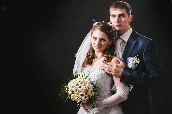 Sposa e sposo che si baciano, che si abbracciano. foto di nozze scattata in studio su sfondo nero — Foto Stock